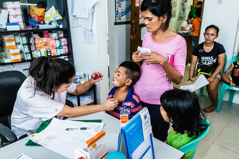 A mother brings her children for check-up and vaccination at the Corazon Aquino Health Center in Baseco Compound, Tondo, Manila. All services are free at the health center.